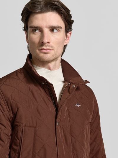 Męski model nosi Regular Fit Kurtka pikowana z wyhaftowanym logo Model 'Windcheater' od Gant, brąz, stójka, wpuszczane i kieszenie z patką, Nahaufnahme Oberkörper.