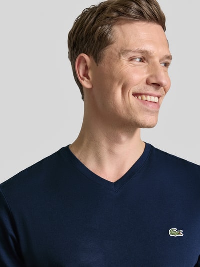 Męski model nosi Regular Fit T-Shirt aus reiner Baumwolle von Lacoste, efekt: jednolity kolor, dekolt w serek, krótki rękaw, wyhaftowane logo, 100% bawełna, zbliżenie na górną część ciała.