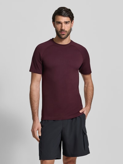 Männermodel trägt Slim Fit T-Shirt mit Logo-Print Modell 'Training Day' von Fabletics, Herren T-Shirt in Dunkelrot, Rundhalsausschnitt, Rückenlänge bei Größe M 71 cm, Ganzkörperansicht von vorne.