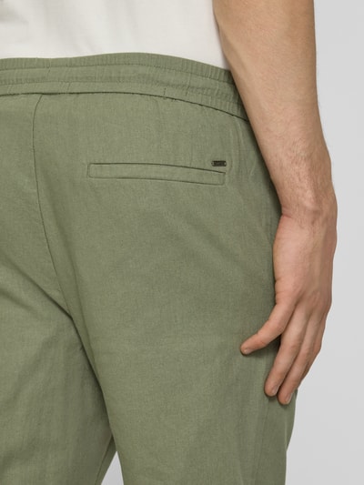 Männermodel trägt Tapered Leinenhose aus Baumwoll-Leinen-Mix Modell 'LINUS' von Only & Sons in Melange-Optik, Detailaufnahme seitlich.