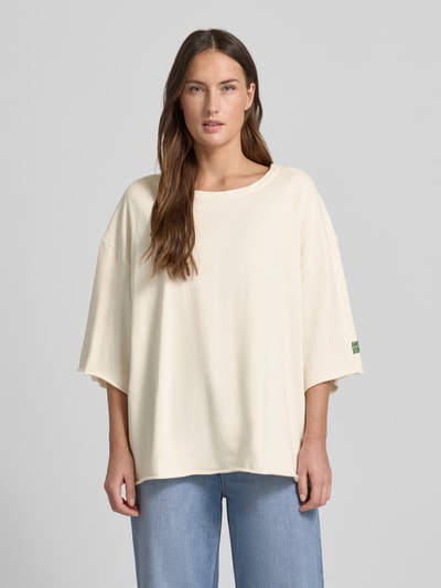 Frauenmodel trägt Oversized T-Shirt mit Label-Print von American Vintage aus reiner Baumwolle in Beige, Nahaufnahme Oberkörper.