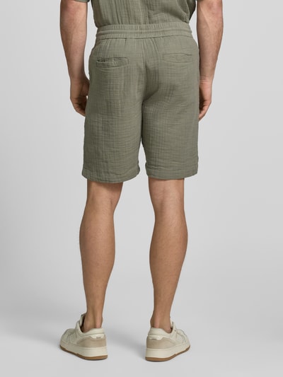 Männermodel trägt Shorts mit Eingrifftaschen und elastischem Bund von Lindbergh aus Reine Baumwolle in Loose-Fit, Rückansicht Ganzkörperansicht.