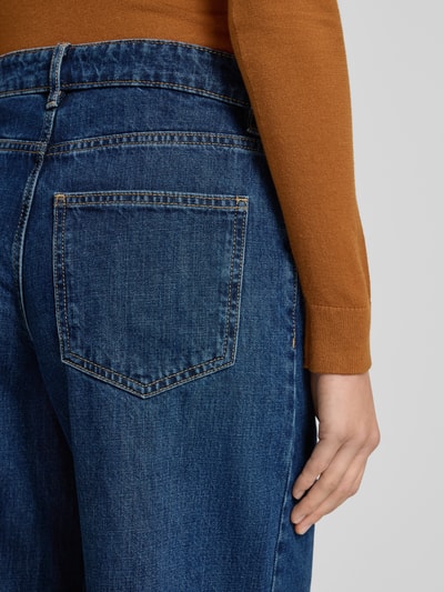 Frauenmodel trägt Jeans mit 5-Pocket-Design Modell 'ANNIE' von Mango aus Reine Baumwolle, blaue Textur, Lockerer-Schnitt, Detailaufnahme Rückansicht.
