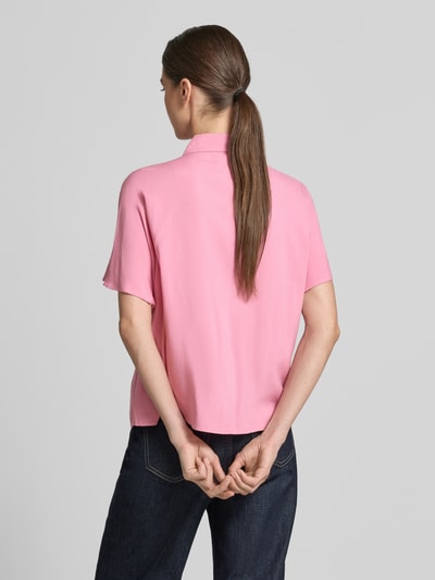 Vrouwenmodel draagt Relaxed Fit Kurzarmbluse aus Viskose van Tom Tailor Denim in effen roze, korte mouwen, eenrijige knopenlijst, hemdkraag, puur viscose, achterkant volledig zichtbaar, geheel van achteren.