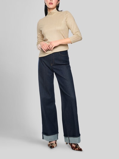 Frauenmodel trägt Longsleeve mit Rollkragen von Marc Cain, beige mit Ripp-Struktur, gerader Schnitt, Glitzer-Garn, Ganzkörperansicht von vorne.
