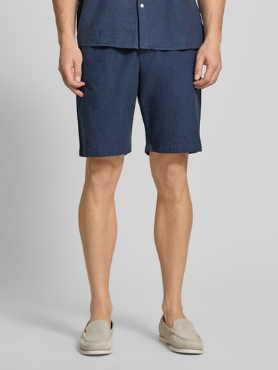 Męski model nosi Shorts aus Leinen-Baumwoll-Mix mit elastischem Bund od MCNEAL w kolorze granatowym, krój regular fit, szerokość w rozmiarze M 44 cm, długość nogawki 23 cm, widok całej sylwetki z przodu.