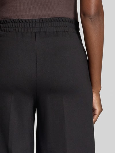 Frauenmodel trägt Wide Fit Hose aus Viskose-Mix von MORE & MORE in Schwarz, elastischer Bund, Detailaufnahme, Nahaufnahme Rückenpartie.