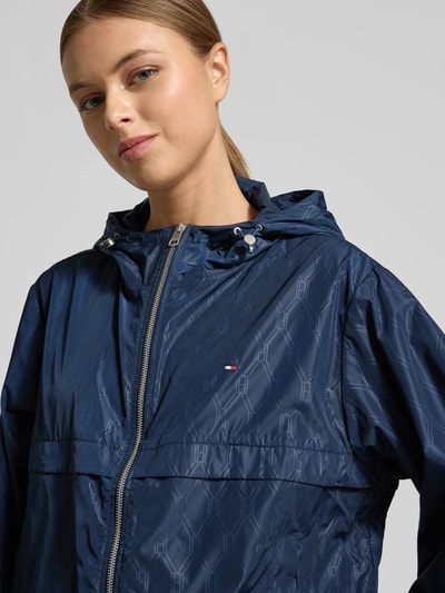 Kobiece modelka nosi Regular Fit Windbreaker mit Kapuze od Tommy Hilfiger, granatowy kolor, logo monogram, wodoodporny, zbliżenie na górną część ciała