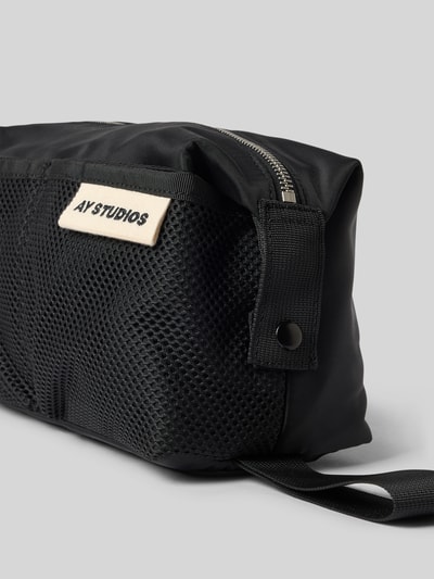 Produktfoto, Kulturtasche mit Logo-Patch von AY STUDIOS in Schwarz, Netztaschen, Reißverschluss, Druckknopfverschluss, Detailaufnahme, Herren-Kulturtasche, Breite 26 cm, Länge 14 cm, Tiefe 12 cm, Schulterriemen 26 cm