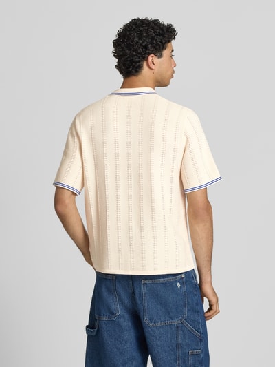 Mannenmodel draagt Regular Fit Poloshirt in Strick-Optik model 'Menton' van Jack & Jones, puur katoen, heren poloshirt, tricotlook, korte mouw, ruglengte bij maat M 70 cm, gebroken wit met blauwe details, rechte lijnen, grof gebreide textuur, ganzkörperansicht rückansicht.