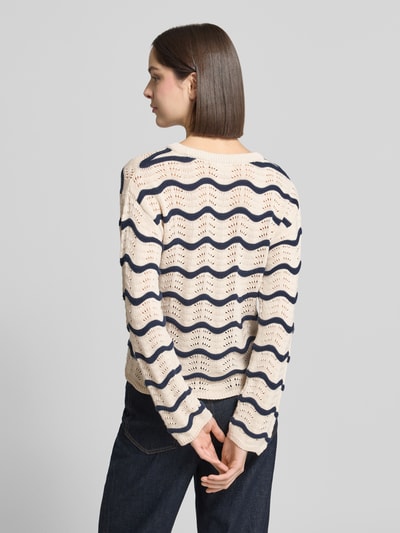 Frauenmodel trägt Regular Fit Pullover in Strick-Optik Modell 'Wave' von Vila, Reine Baumwolle, Lochmuster, Wellenmuster, Rundhalsausschnitt, Taillierte Passform, Rückenlänge 54 cm, Ärmellänge 63 cm, Farbkontrast Creme und Dunkelblau, Struktur durch Lochmuster, Ganzkörperansicht Rückansicht.