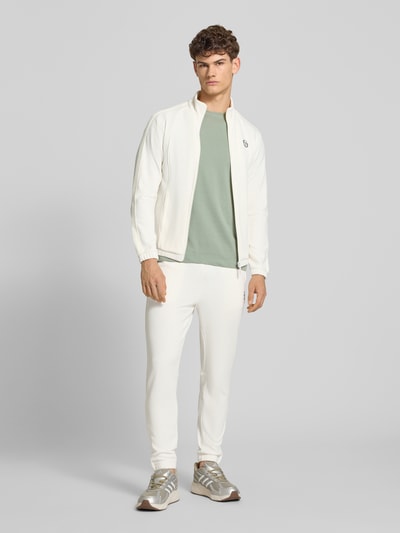 Mannelijk model draagt Slim Fit Tracksuit met Logo-Stitching model 'Egeo' van SERGIO TACCHINI in crème, katoenmix en elastische boorden, opstaande kraag, ritssluiting, slim fit, bandwijdte maat M 42 cm, ruglengte 64 cm, schouderbreedte 46 cm, mouwlengte 67 cm, binnenbeenlengte 73 cm, geheel in beeld van voren.