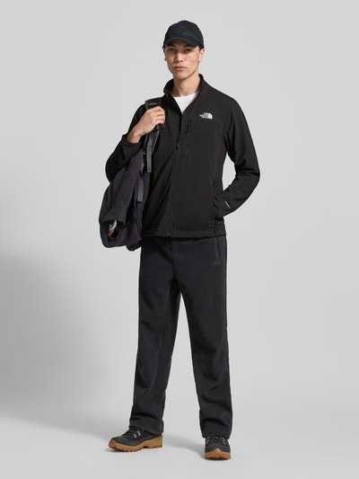 Mężczyzna nosi Jacke mit Stehkragen und Logo von The North Face, mieszanka materiałów z dodatkiem streczu, krój regular fit, stójka, zamek błyskawiczny, logo, kieszenie zapinane na zamek błyskawiczny, długość tyłu w rozmiarze M: 71 cm, szerokość ramion w rozmiarze M: 46 cm, szerokość klatki piersiowej w rozmiarze M: 56 cm, długość rękawów w rozmiarze M: 58 cm, kolor czarny, pełny widok od przodu
