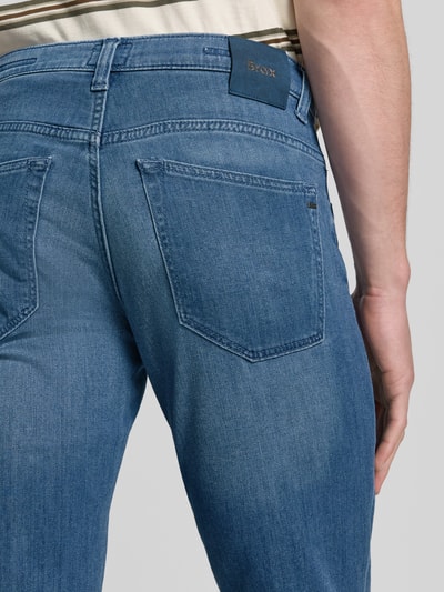 Männermodel trägt Regular Fit Jeans aus Baumwoll-Mix mit Viskose-Seiden-Anteil Modell 'Chuck' von Brax in Denim-Optik mit Label Patch, 5-Pocket-Design, Twill-Struktur, Nahaufnahme Rückansicht.