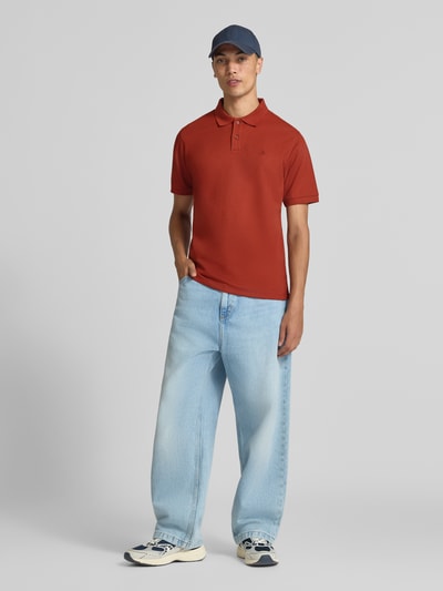 Männermodel trägt Slim Fit Poloshirt mit Label-Stitching Modell 'AUSTIN' von JACK & JONES, rot, stretchiger Baumwoll-Mix, Ganzkörperansicht von vorne.
