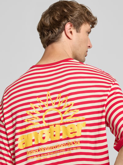Mężczyznamodel nosi T-Shirt mit Streifenmuster und Label-Print von ANOTHER COTTON LAB z bawełny, krój relaxed fit, wzór w paski, nadruk z logo, okrągły dekolt, długość tyłu w rozmiarze M: 65 cm, widok całych pleców