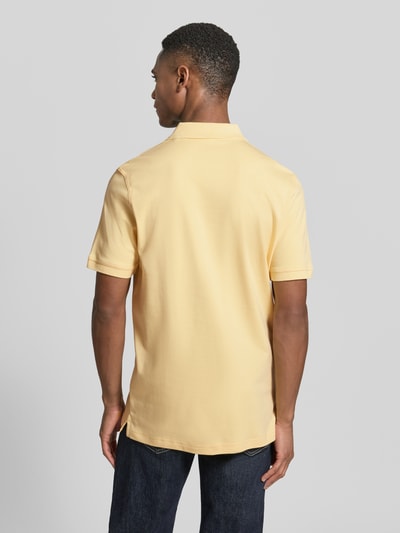 Männermodel trägt Regular Fit Poloshirt mit Logo-Stitching von Fynch-Hatton in Gelb aus reiner Baumwolle, Rückenansicht Ganzkörperansicht.