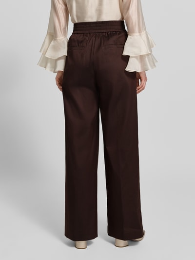 Kobiece model nosi spodnie materiałowe 'Stoffhose mit französischen Eingrifftaschen' od Windsor, mieszanka bawełny z dodatkiem streczu, krój wide fit, ciemny brąz, kieszenie z wypustkami z tyłu, szerokość w rozmiarze 36: 36 cm, długość wewnętrzna nogawki: 82 cm, widok całej sylwetki z tyłu.