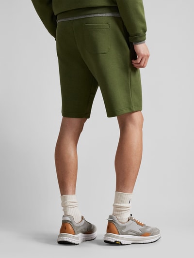 Männermodel trägt Regular Fit Sweatshorts aus Baumwoll-Mix von Polo Ralph Lauren in Olivgrün, unifarben, Sweatstruktur, Ganzkörperansicht Rückansicht.