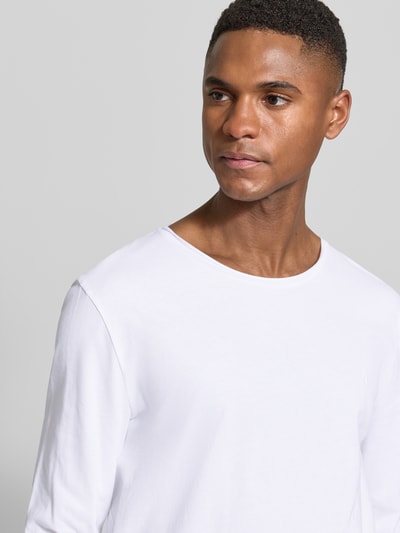 Männermodel trägt weißes Regular Fit Langarmshirt aus reiner Bio-Baumwolle Modell 'JAAMES' von Armedangels, Nahaufnahme Oberkörper.