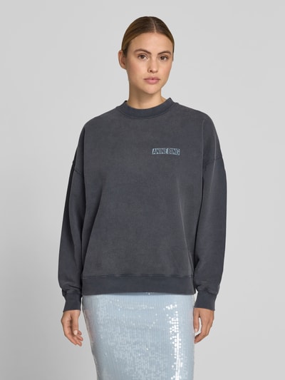 Frauenmodel trägt Regular Fit Sweatshirt mit Logo-Print von Anine Bing, reine Baumwolle, dunkles Grau, Rundhalsausschnitt, elastische Abschlüsse, Ganzkörperansicht von vorne.