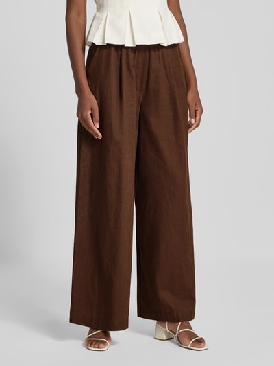 Frauenmodel trägt Wide Fit Leinen-Hose aus Leinen-Mix von Rich & Royal in Braun, weitem Schnitt, elastischer Bund, Nahaufnahme Oberkörper. Damen Leinenhose mit Baumwoll-Anteil, Bundfalten, Bundweite 35 cm, Innenbeinlänge 76 cm.