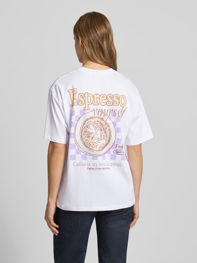 Kobiece model prezentuje damski t-shirt z bawełny model 'LATTE' od JJXX, biały z nadrukiem z tyłu, krój loose fit, okrągły dekolt, długość tyłu w rozmiarze S: 65 cm, widok całej sylwetki z tyłu.