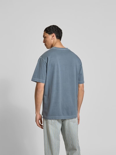 Männermodel trägt Regular Fit T-Shirt aus reiner Baumwolle von Closed in Blau mit Used-Look und Label-Print, Ganzkörperansicht Rückansicht.