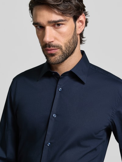 Męski model nosi Slim Fit Businesshemd aus Baumwoll-Mix Modell 'H-HANK' od BOSS, granatowy, popelina, unikolor, koszula biznesowa, krój slim fit, kołnierzyk kent, długi rękaw, mankiet sportowy, przód zapinany na guziki, widok na górną część tułowia z przodu.