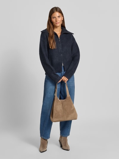 Kobiece modelka nosi torebkę 'Handtasche aus echtem Leder' od Coccinelle w odcieniu beżowym, z detalem z logo, Główna przegroda z zapięciem na magnes, wyjmowana przegródka wewnętrzna, naturalna skóra, Szerokość w rozmiarze 1: 32 cm, Długość w rozmiarze 1: 28 cm, Głębokość w rozmiarze 1: 51 cm, długość paska na ramię w rozmiarze 1: 31 cm, pełny widok z przodu.