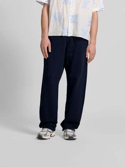 Männermodel trägt Wide Fit Sweatpants mit Eingrifftaschen von Kenzo aus reiner Baumwolle in Dunkelblau, Ganzkörperansicht von vorne.