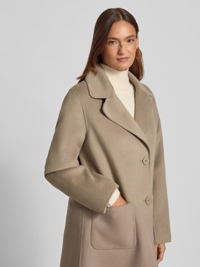 Frauenmodel trägt Regular Fit Mantel aus Woll-Mix mit Reverskragen von Fuchs Schmitt in Beige, große aufgesetzte Taschen, Nahaufnahme Oberkörper. Rückenlänge 102 cm, Schulterbreite 50 cm, Brustweite 58 cm, Ärmellänge 65 cm bei Größe 36.