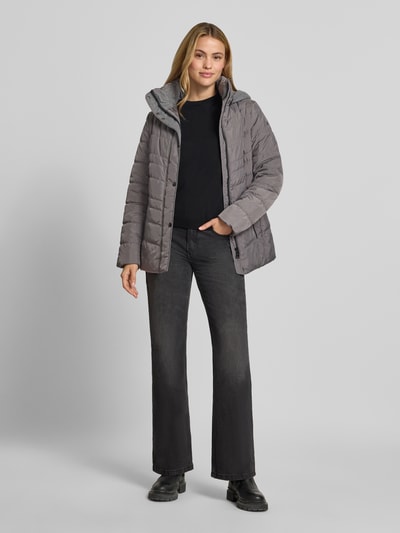 Kobiece modelka nosi Jacke in Stepp-Optik mit Kapuze od FUCHS SCHMITT, szara, taliowany krój, kaptur, wpuszczane kieszenie z zamkiem błyskawicznym, długość tyłu w rozmiarze 36: 74 cm, szerokość ramion w rozmiarze 36: 40 cm, szerokość klatki piersiowej w rozmiarze 36: 48 cm, długość rękawów w rozmiarze 36: 64 cm, widok całej sylwetki z przodu.