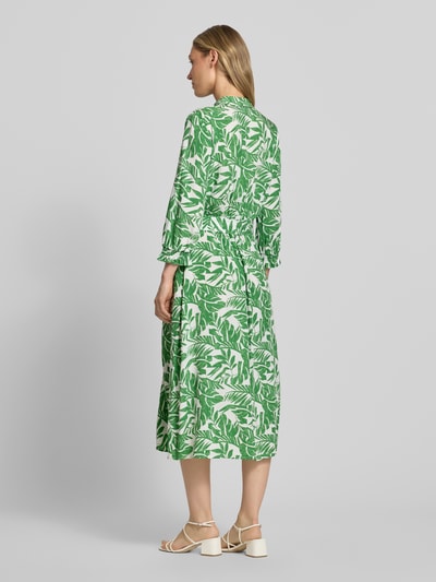 Modelka kobieca nosi Midikleid aus reiner Viskose mit Umlegekragen od More & More, zielono-biały kwiatowy wzór, długość midi, widok całej sylwetki z tyłu. Szerokość w rozmiarze 36: 40 cm, długość pleców: 125 cm, rękaw: 49 cm, krój dopasowany, zdejmowany pasek w talii, półrękaw, zapięcie na guziki, elastyczne mankiety.