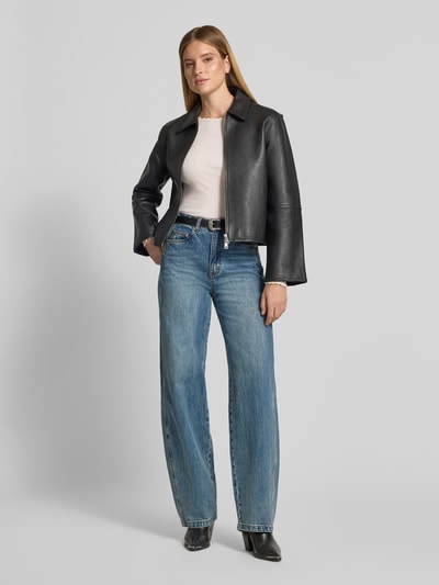 Frauenmodel trägt Slim Fit Longsleeve aus Baumwoll-Mix von Lanius in Beige, kombiniert mit Jeans und schwarzer Jacke, Ganzkörperansicht von vorne. Elastischer Baumwoll-Mix, U-Boot-Ausschnitt, Rüschsaum, Rückenlänge 54 cm bei Größe 36.