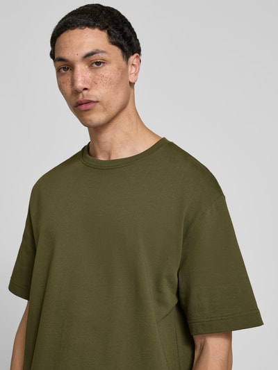 Männermodel trägt T-Shirt mit Rundhalsausschnitt von Filippa K in Olivgrün, Relaxed Fit, reine Baumwolle, Nahaufnahme Oberkörper.