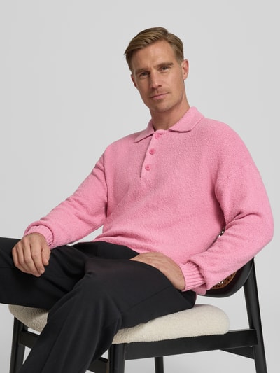 Męski model nosi Strickpullover mit Polokragen Modell 'Bekket' od Drykorn, różowy sweter, bawełniany mix, relaxed fit, ujęcie całej sylwetki z przodu.