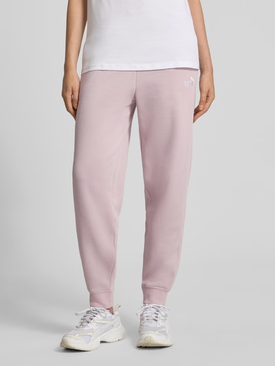 Vrouwenmodel draagt sweatpants met labelstitching en elastische band van PUMA in katoenmix, relaxed fit, lichtroze tint, volledige vooraanzicht