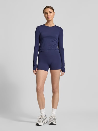 Frauenmodel trägt Slim Fit Shorts mit breitem Bund Modell 'Scrunch' von Fabletics im Elastischer-Material-Mix, Dunkelblau, Ganzkörperansicht von vorne.
