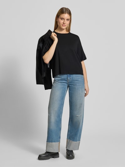 Frauenmodel trägt Boxy Fit T-Shirt aus Bio-Baumwolle Modell 'Derby' von Soyaconcept in Schwarz, kombiniert zu Jeans. Damen T-Shirt mit Rundhalsausschnitt, Rückenlänge bei Größe S 57 cm, Ganzkörperansicht von vorne.