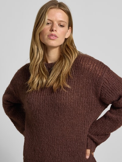 Frauenmodel trägt braunen Relaxed Fit Pullover im Chunky Knit Look Modell 'DORTHEA' von PIECES, grobe Strickstruktur, Nahaufnahme Oberkörper. Damen Pullover von PIECES.