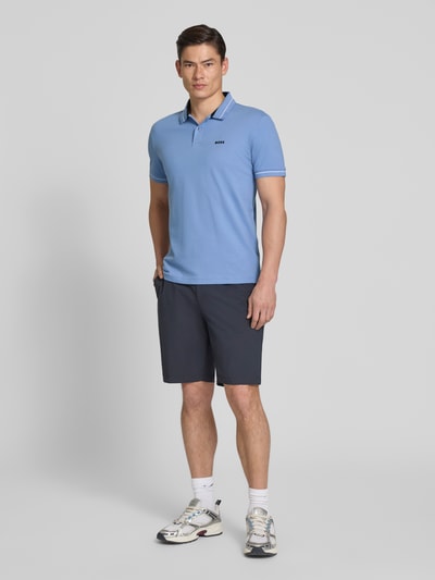 Męski model nosi Regular Fit Poloshirt aus Baumwoll-Mix Modell 'PL_Member' od BOSS Green w kolorze jasnoniebieskim, kontrastowe detale, gładka faktura, logo na piersi, krótki rękaw, piqué, widok całej sylwetki z przodu.