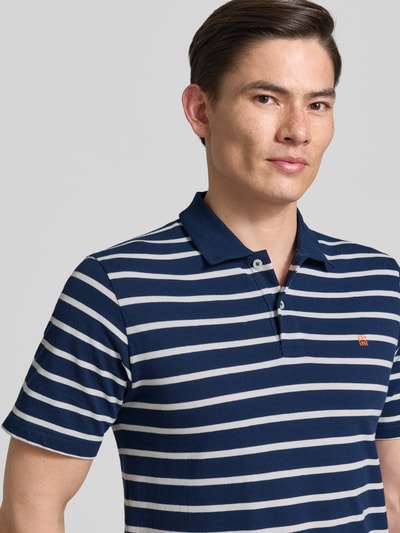 Männermodel trägt Regular Fit Poloshirt mit Logo-Stitching Modell 'Adam' von Jack & Jones Premium, blaue Streifen, Nahaufnahme Oberkörper.