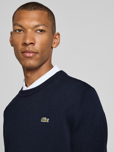 Männermodel trägt dunkelblauen Regular Fit Pullover aus Baumwoll-Mix von Lacoste, weiße Kragen-Details, Nahaufnahme Oberkörper, Herren Pullover von Lacoste
