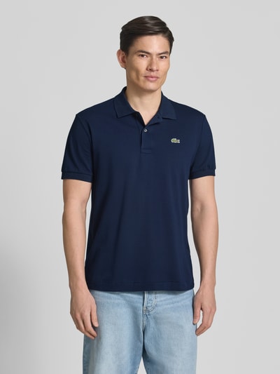 Männermodel trägt Regular Fit Poloshirt aus Baumwoll-Mix von Lacoste, dunkelblau, unifarben, kurzarm, Logo-Detail, Ganzkörperansicht von vorne.