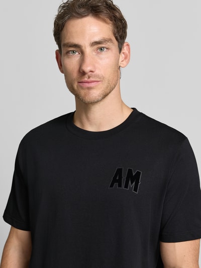 Mannelijk model draagt Relaxed Fit T-shirt uit puur katoen van Antony Morato in zwart met labelpatch, ronde hals, nahaufnahme bovenlichaam. Heren t-shirt, ruglengte maat M 70 cm.