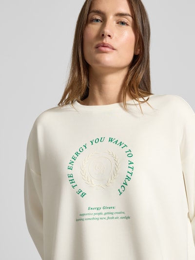 Vrouwenmodel draagt Sweatshirt met Bändel und Frontprint van Christian Berg Woman, crèmekleurig, modal-mix, ronde hals, oversized, Nahaufnahme bovenlichaam.