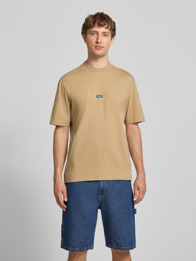 Männermodel trägt Regular Fit T-Shirt aus reiner Baumwolle Modell 'NIEROS' von HUGO in Beige, kombiniert mit Jeans-Shorts, Ganzkörperansicht von vorne, Herren T-Shirt von HUGO Blue.