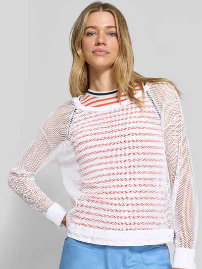 Frauenmodel trägt Longsleeve mit Lochmuster von Marc Cain in Weiß mit transparentem Design, lockerem Schnitt und Tunnelzugbund, Nahaufnahme Oberkörper.