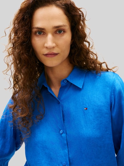 Frauenmodel trägt Relaxed Fit Langarmbluse aus reinem Leinen von Tommy Hilfiger in Optik: Unifarben, Kragenform: Hemdkragen, Logo-Stitching, Verschluss: Knopfleiste, Ärmelform: Langarm, Ärmelabschluss: Manschette, Rumpfabschluss: abgerundet, Materialverarbeitung: Flammgarn, Ganzkörperansicht von vorne.